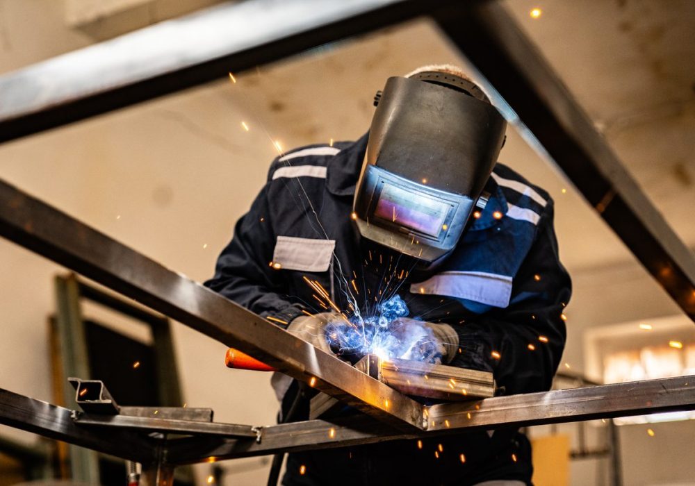 Senior man welding at his work place.  He is dressed in work suit.